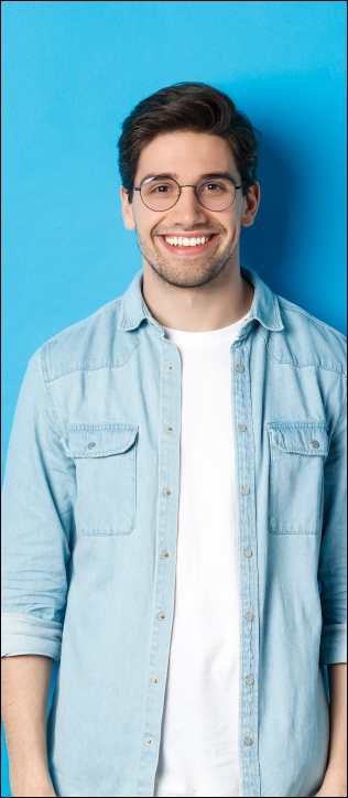 young-modern-man-glasses-casual-outfit-standing-against-blue-background-smiling-happy-camera.png